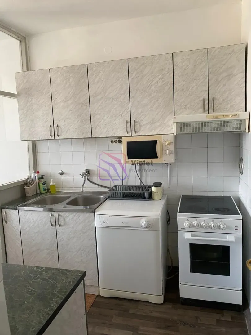 Manja kuhinja sa sudoperom, šporetom i visećim elementima.