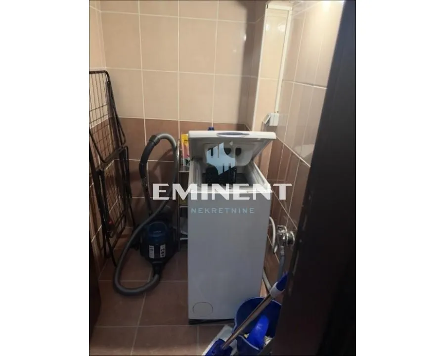 Bathroom with a washing machine and wall tiles.
