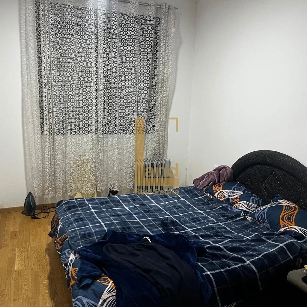 Spavaća soba sa bračnim krevetom, prozorom sa zavjesama i laminatom.
