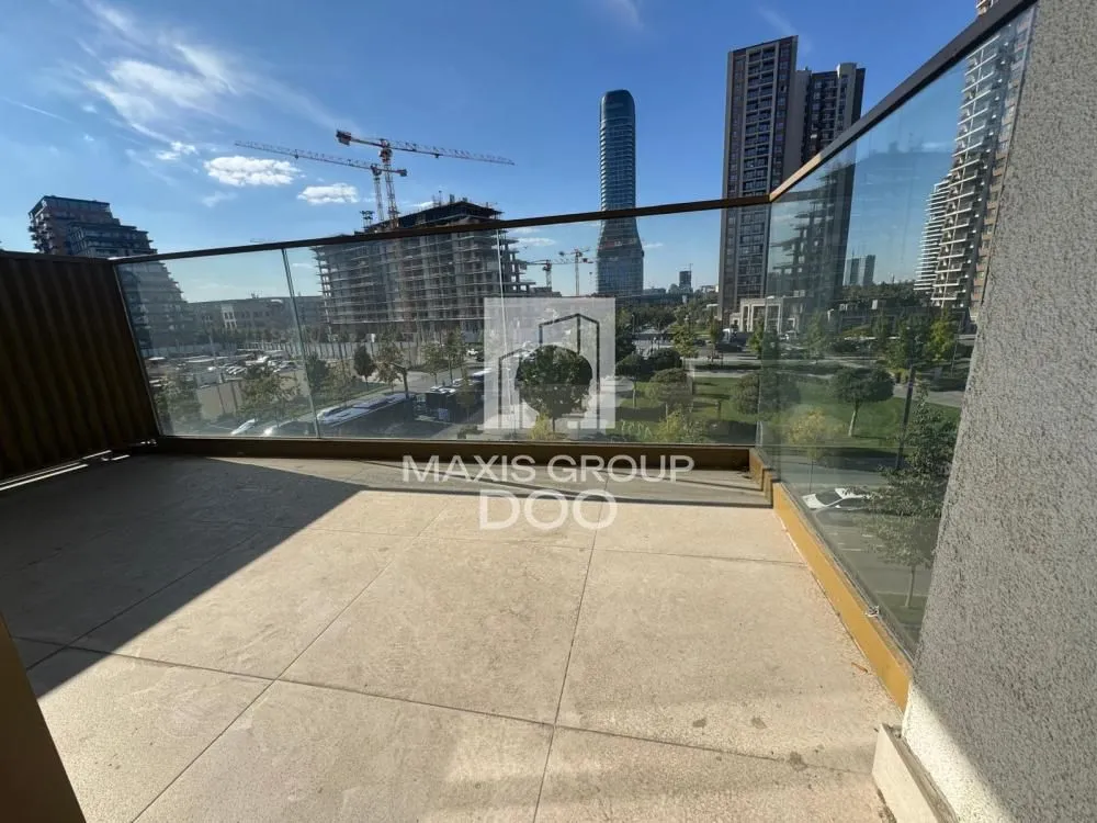 Spacious balcony with a glass railing and city views.