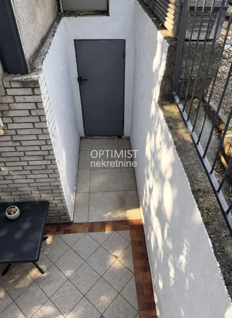 Ulaz u suteren sa metalnim vratima i popločanim prolazom.
