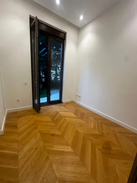 Prazna soba sa drvenim parketom i balkonskim vratima. - image 2