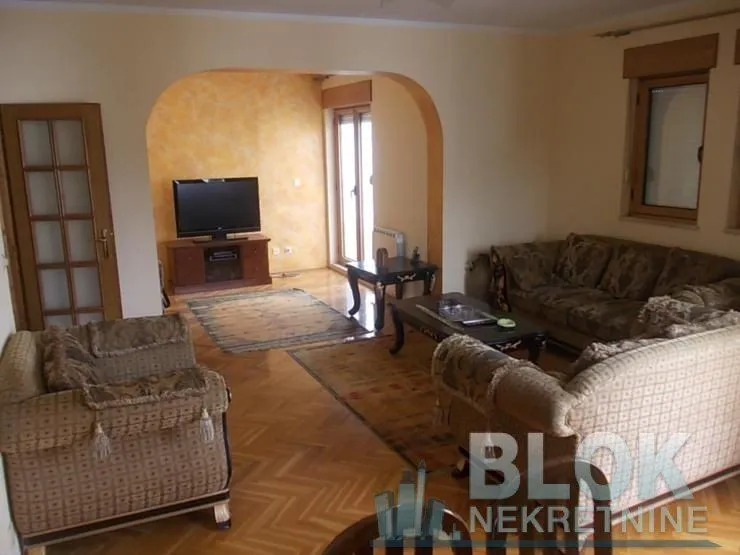 Living room with seating furniture, television, and parquet flooring.