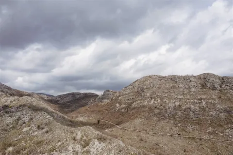 Široki pogled na brdoviti i stjenoviti predio pod oblačnim nebom. - image 8