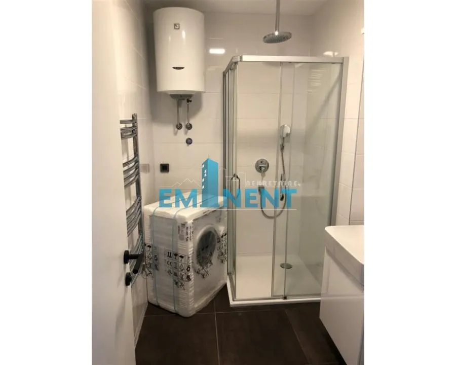 Bathroom with a shower cabin, water heater, and washing machine.