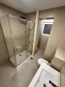 Moderno kupatilo sa tuš kabinom, umivaonikom i toaletom u bež pločicama. - image 10