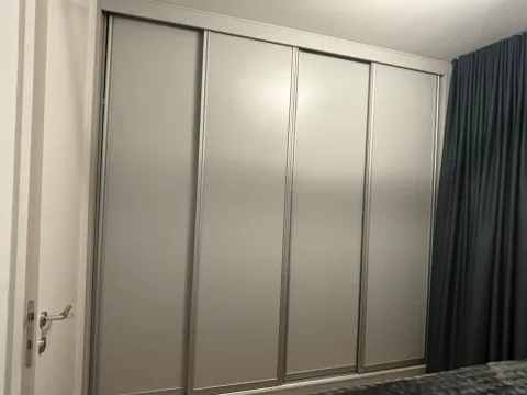 Bedroom with a large built-in wardrobe with sliding doors. - image 9