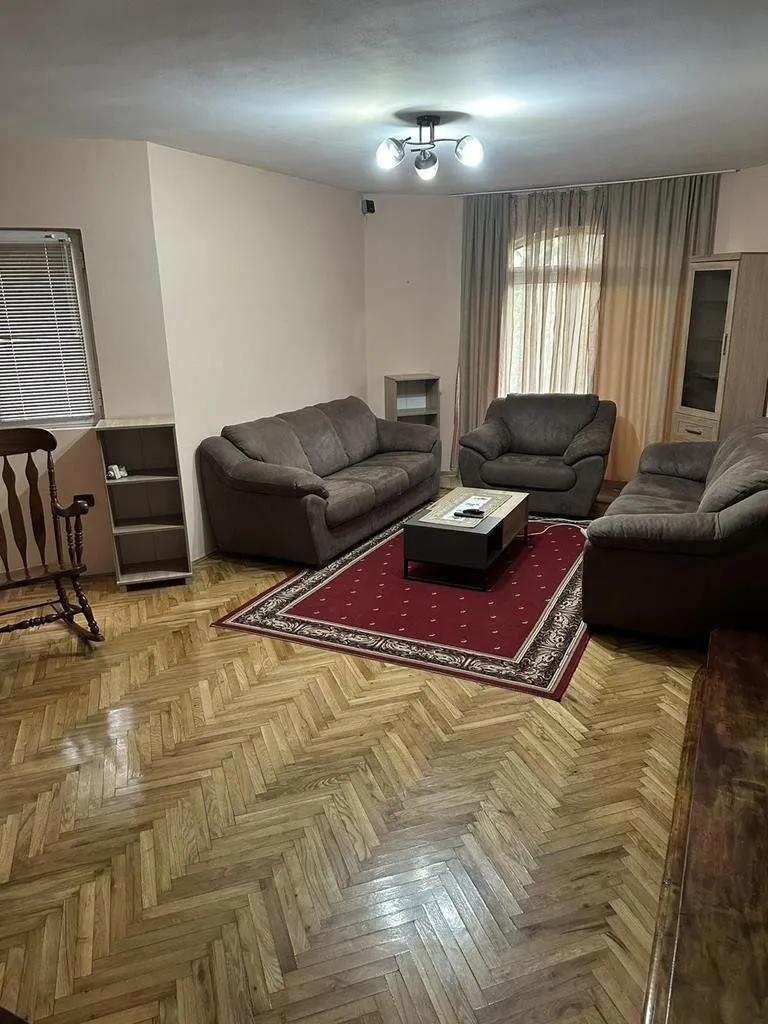Living room furnished with seating sets and hardwood flooring.