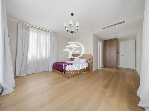 Prostrana spavaća soba sa bračnim krevetom, drvenim podom i velikim prozorom sa belim zavesama. - image 9