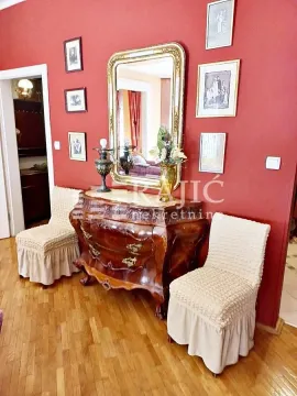 Living room with red walls, chest of drawers, mirror, and slipcovered chairs. - image 4