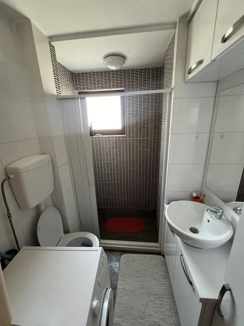 Small and functional bathroom with a shower cabin and a washing machine.