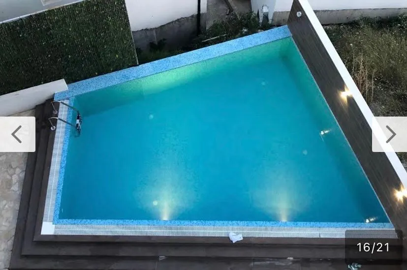 Pogled odozgo na spoljni bazen sa plavim pločicama i osvjetljenjem.