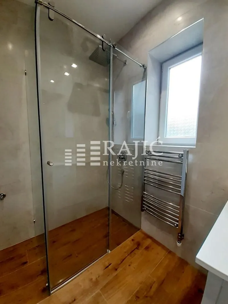 Modern bathroom with a walk-in shower and wooden flooring.
