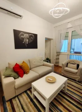 Living room with a sofa, coffee table, and an elephant picture on the wall. - image 4