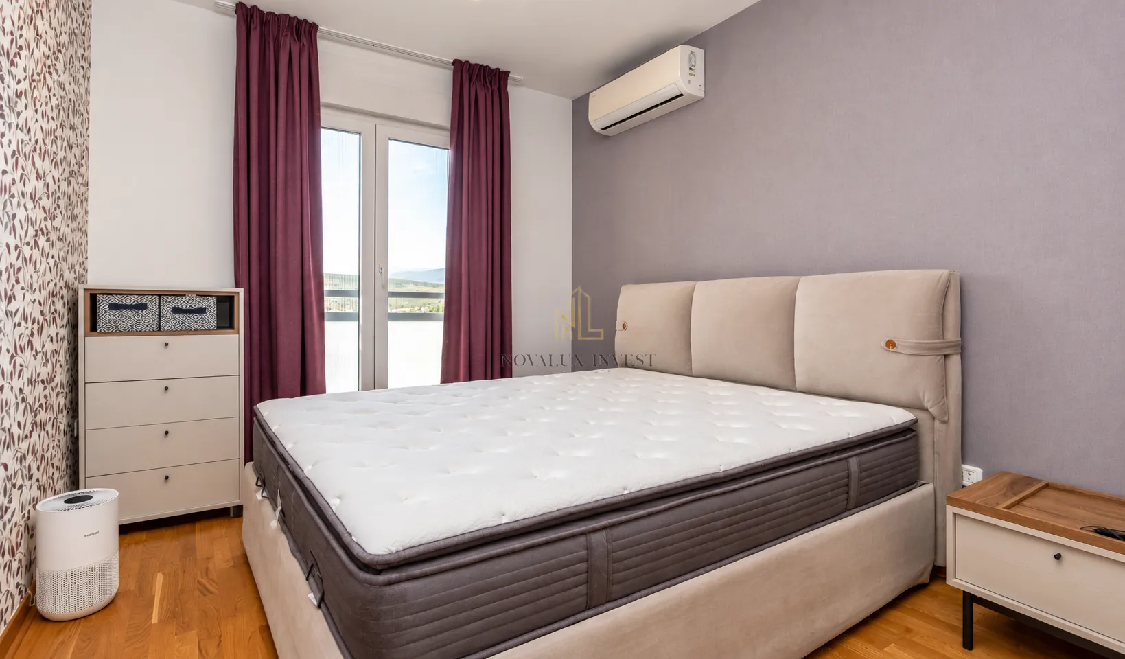 Spavaća soba sa bračnim krevetom, komodom i izlazom na balkon.
