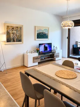 Dnevna soba sa trpezarijom, TV komodom i umjetničkim slikama na zidu. - image 3