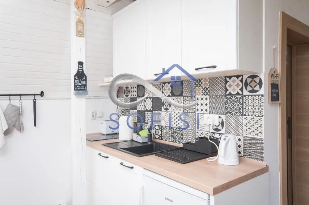 Part of the kitchen with white cabinetry, a sink, and decorative wall tiles.