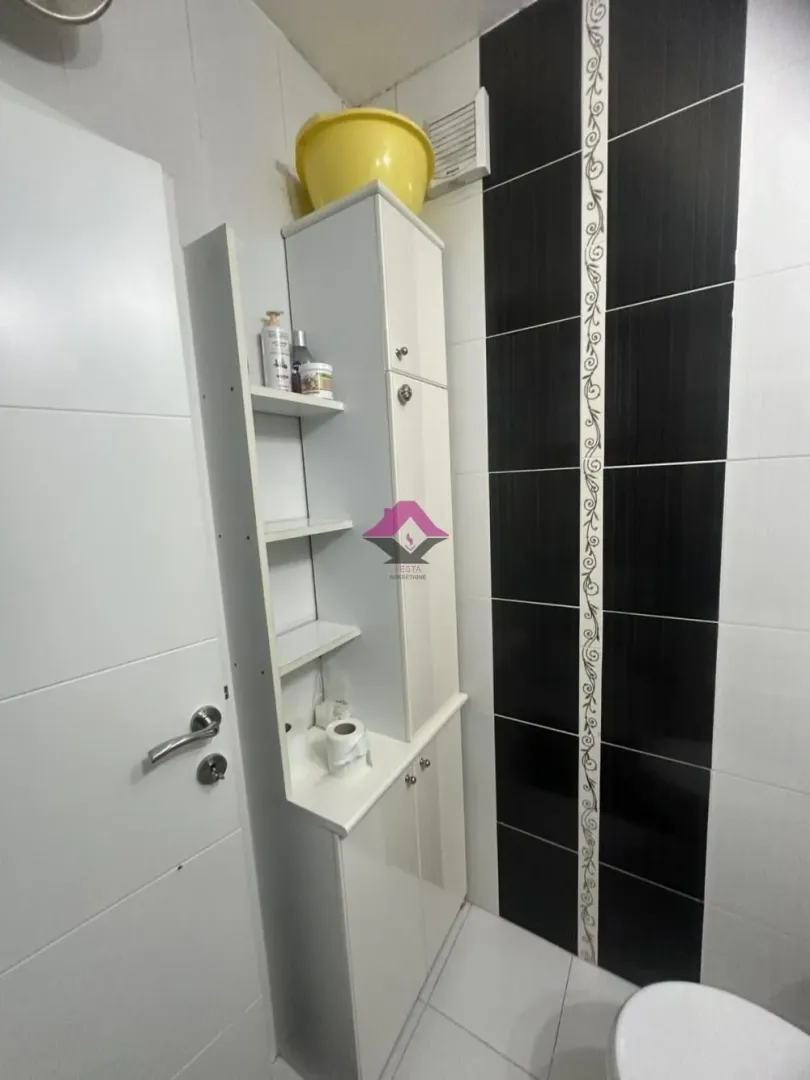 Small bathroom with white furniture and black and white wall tiles.