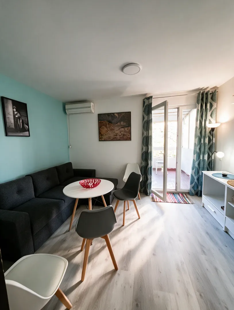 Living room with a sofa, dining table, and access to the terrace.