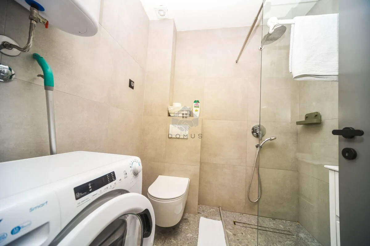 Kompaktno kupatilo sa tuš kabinom, wc šoljom i veš mašinom.