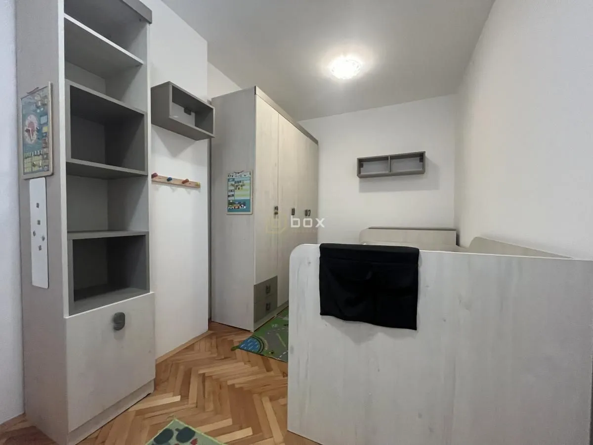 Children's bedroom furnished with a bed, wardrobe, and bookshelf.