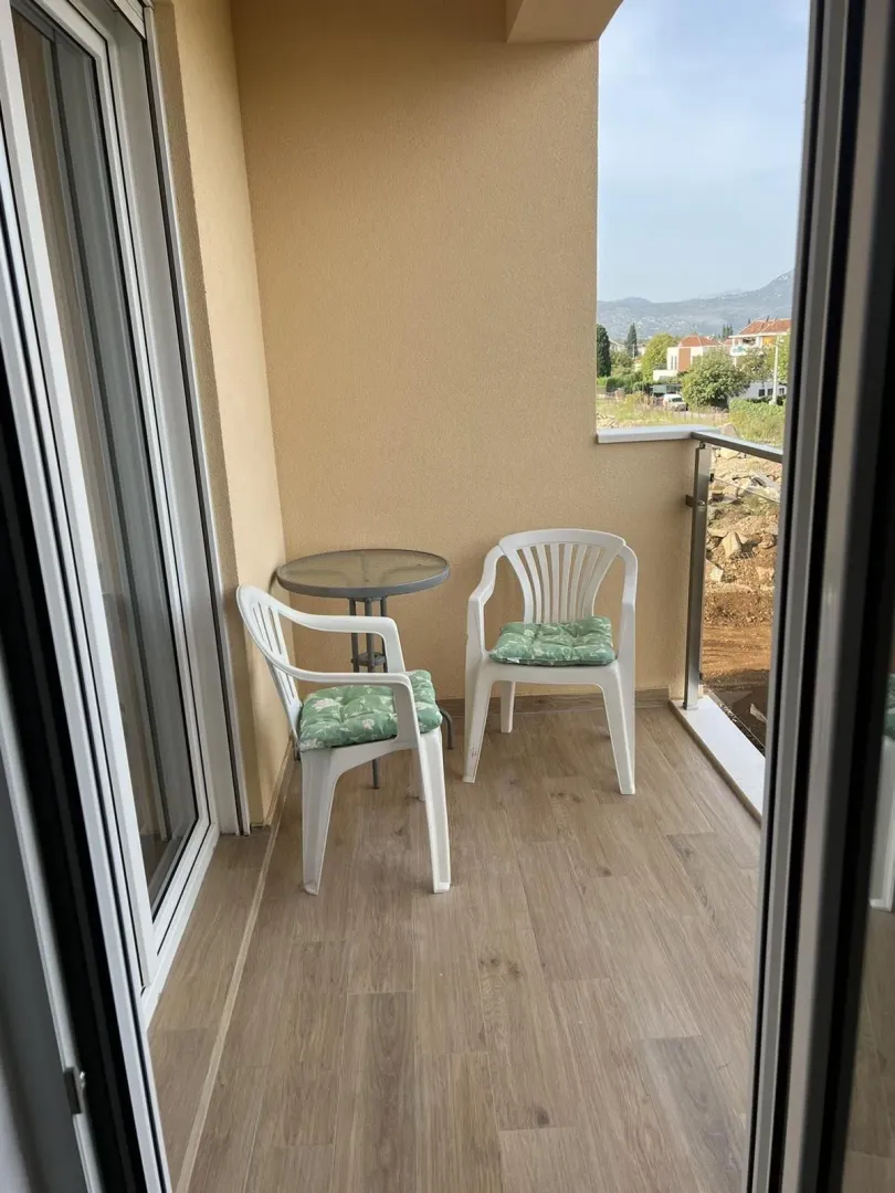 Balcony with two white chairs and a small round table.