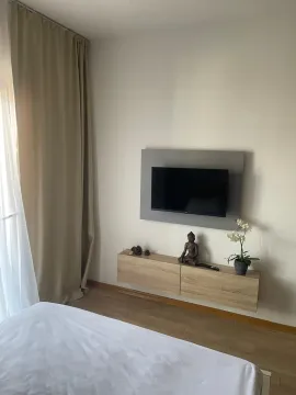 Uređena spavaća soba sa krevetom, TV-om na zidu i visećom komodom. - image 4