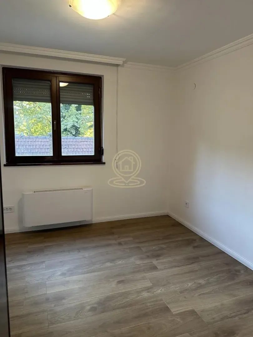 Empty room with a window and laminate flooring.