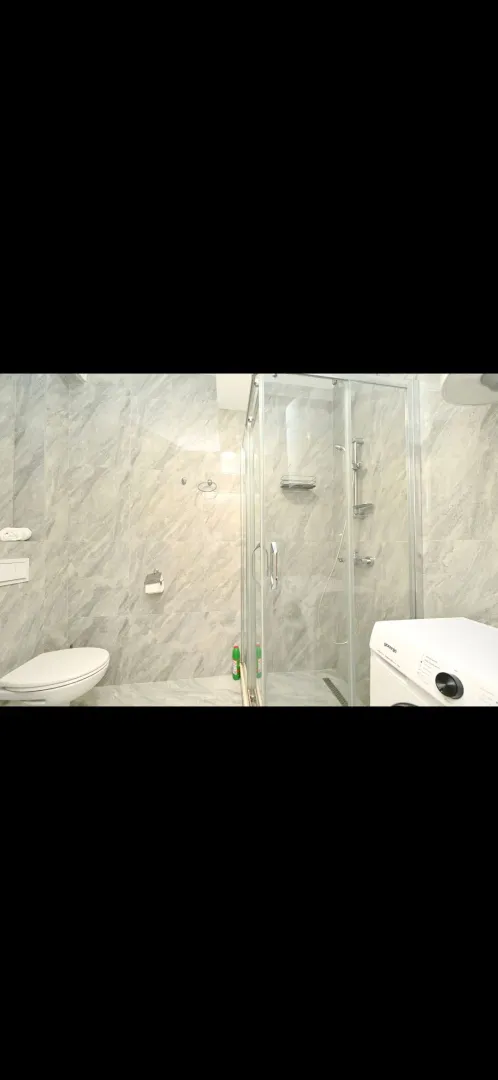 Modernly equipped bathroom with a shower cabin and ceramic tiles.