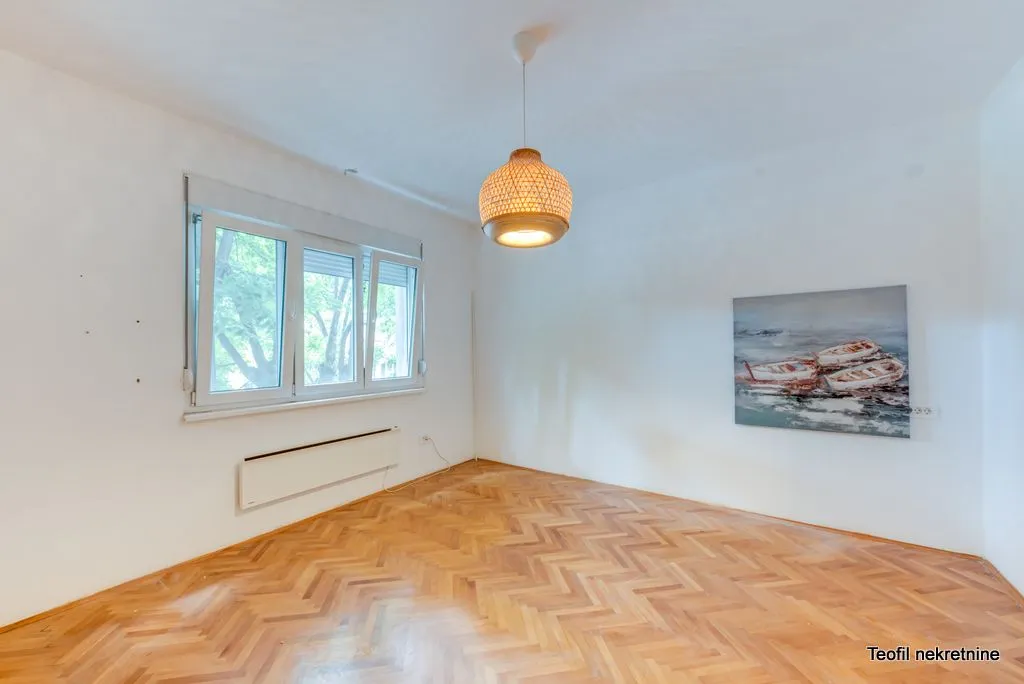 Empty room with parquet flooring and a hanging lamp.