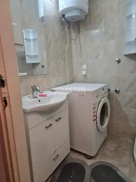 Kupatilo opremljeno umivaonikom, veš mašinom i pločicama. - image 11