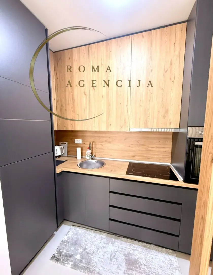 Moderna kuhinja sa tamnim elementima i drvenim detaljima.
