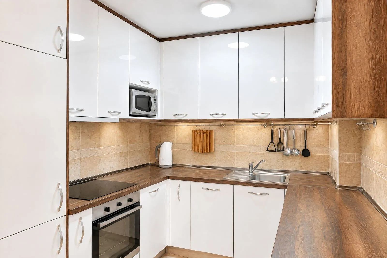 Modern kitchen with white cabinets, wooden countertops, and a built-in oven.