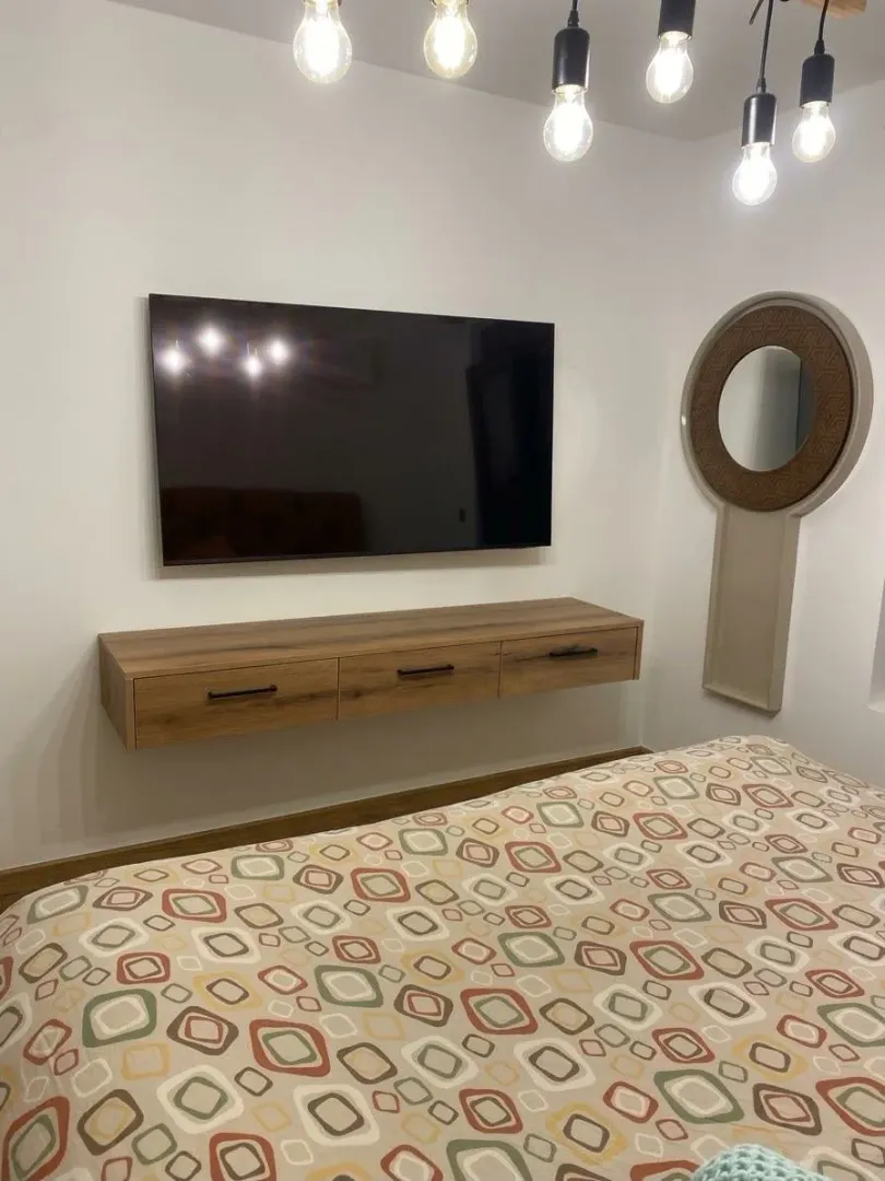 Furnished bedroom with a bed, TV, and decorative mirror.