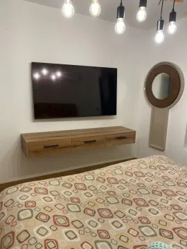 Furnished bedroom with a bed, TV, and decorative mirror. - image 8