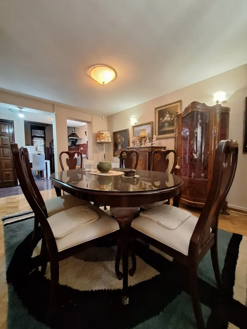 Dining area with a wooden table, chairs, and a traditional-style display cabinet.
