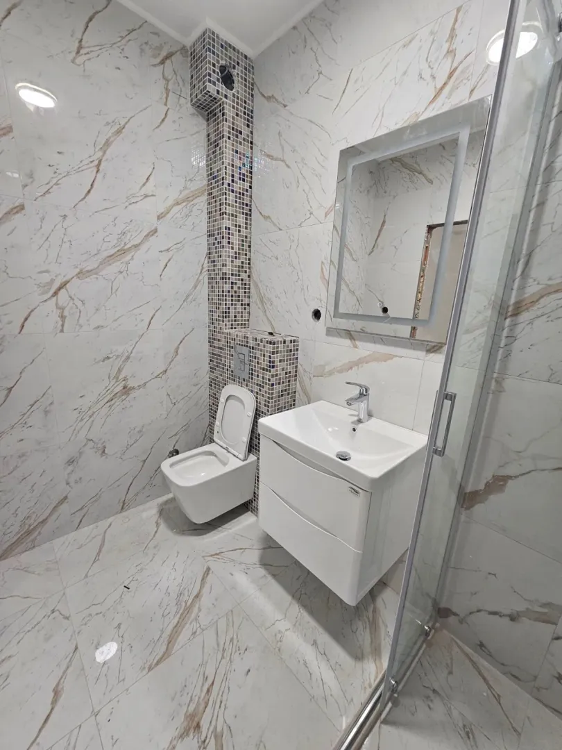 Moderne renovirano kupatilo sa umivaonikom, wc šoljom i tuš kabinom.
