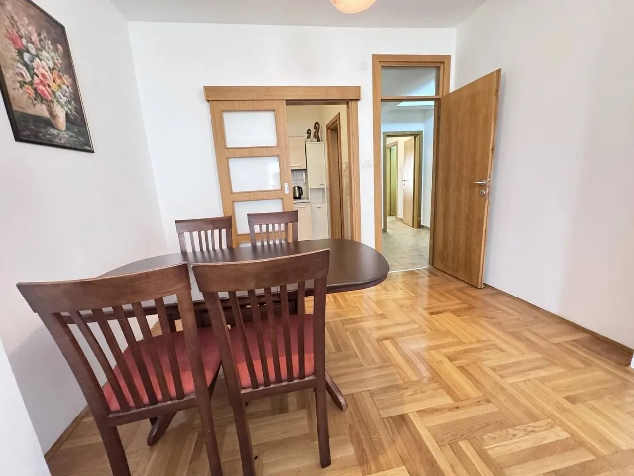 Dining room with a wooden table and chairs and parquet flooring.