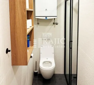 Modern bathroom with a shower cabin, toilet, and water heater. - image 14