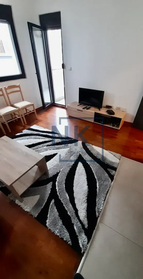 Dnevna soba sa televizorom, stočićem i izlazom na terasu.