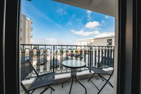 Small furnished balcony with a table and two chairs and a view of the parking lot and surrounding buildings. - image 19