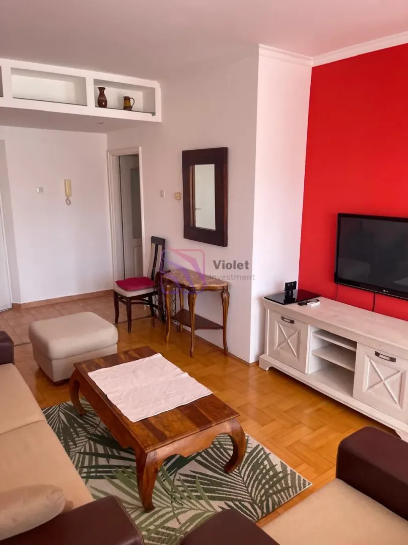 Living room with sofa set, TV unit, and red accent wall.