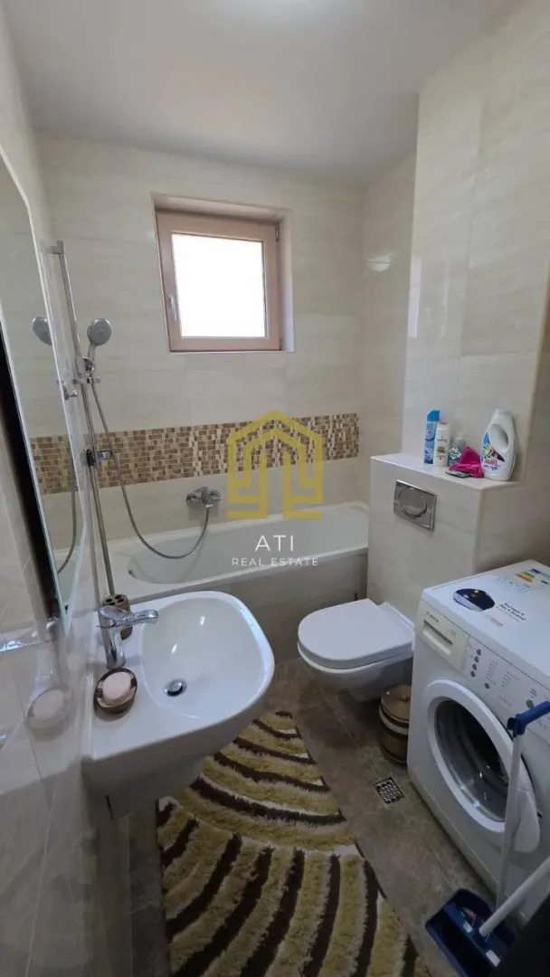 Manje kupatilo sa kadom, umivaonikom, WC šoljom i veš mašinom.