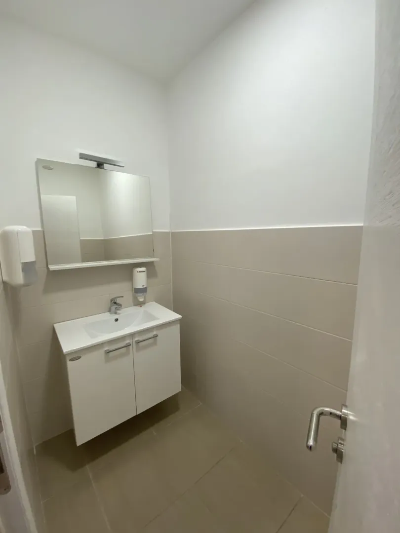 A small and tidy bathroom featuring a white vanity sink, cabinet, and mirror.