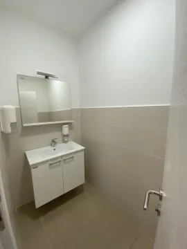 A small and tidy bathroom featuring a white vanity sink, cabinet, and mirror. - image 24