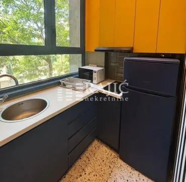 Small kitchen with yellow upper cabinets and dark lower cabinets next to the window. - image 10
