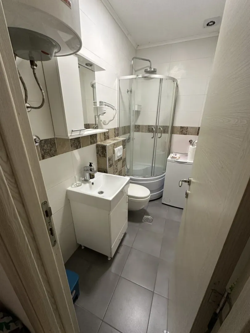 Small bathroom with a shower cabin, washbasin, and washing machine.