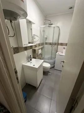 Small bathroom with a shower cabin, washbasin, and washing machine. - image 6