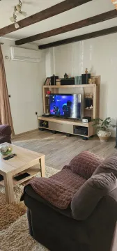 Dnevna soba sa garniturom, TV komodom i drvenim gredama na plafonu. - image 12