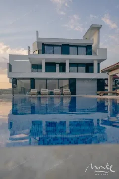 View of a modern villa with a swimming pool and sun loungers in the yard. - image 25